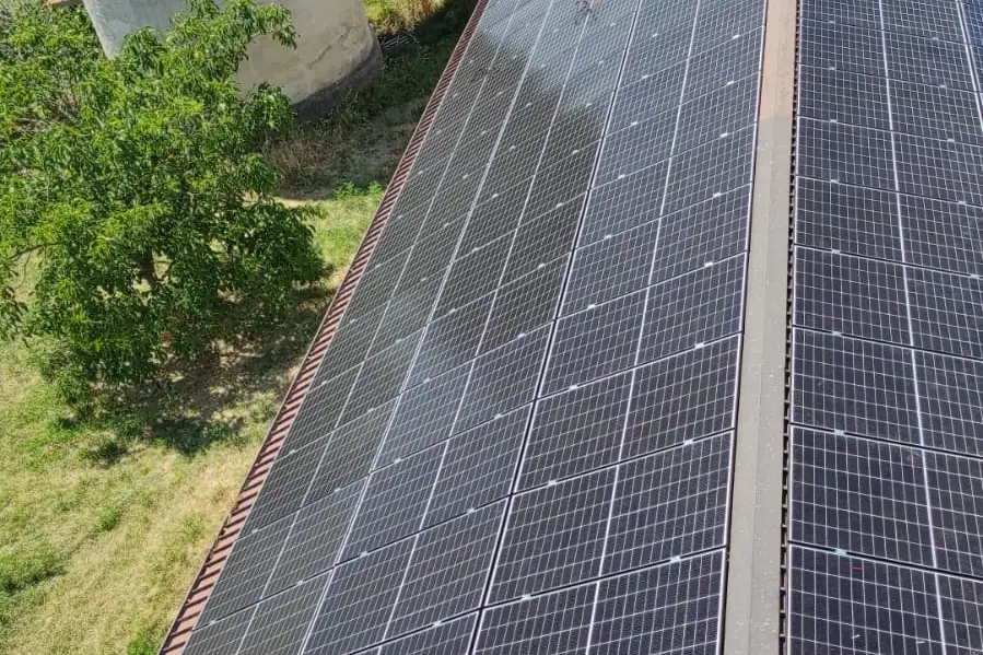 Copertura di un capannone agricolo interamente coperta da moduli fotovoltaici, con i campi coltivati intorno