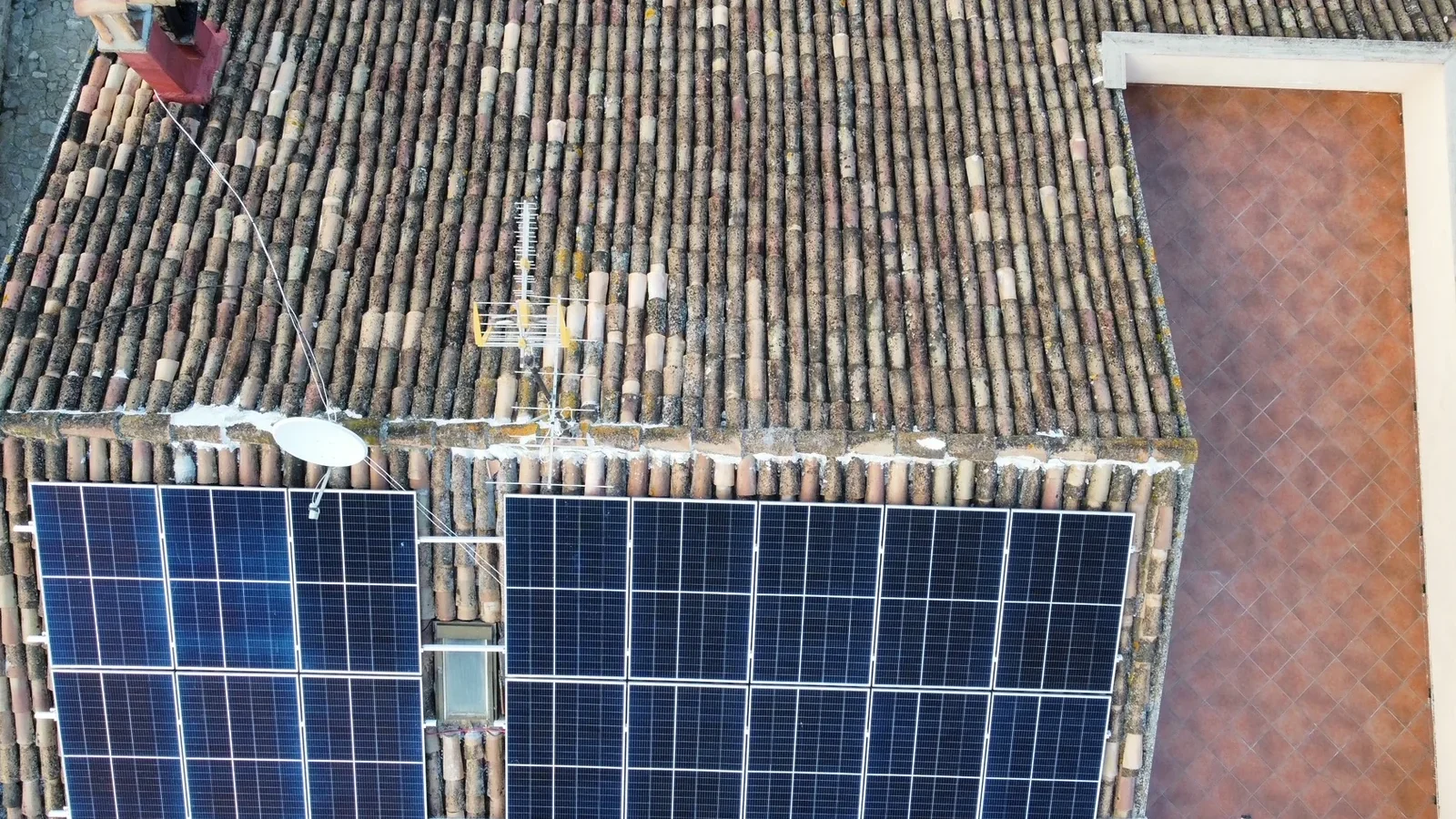 Vista dall'alto dei due campi di moduli fotovoltaici posati sulla falda in coppi di un'abitazione