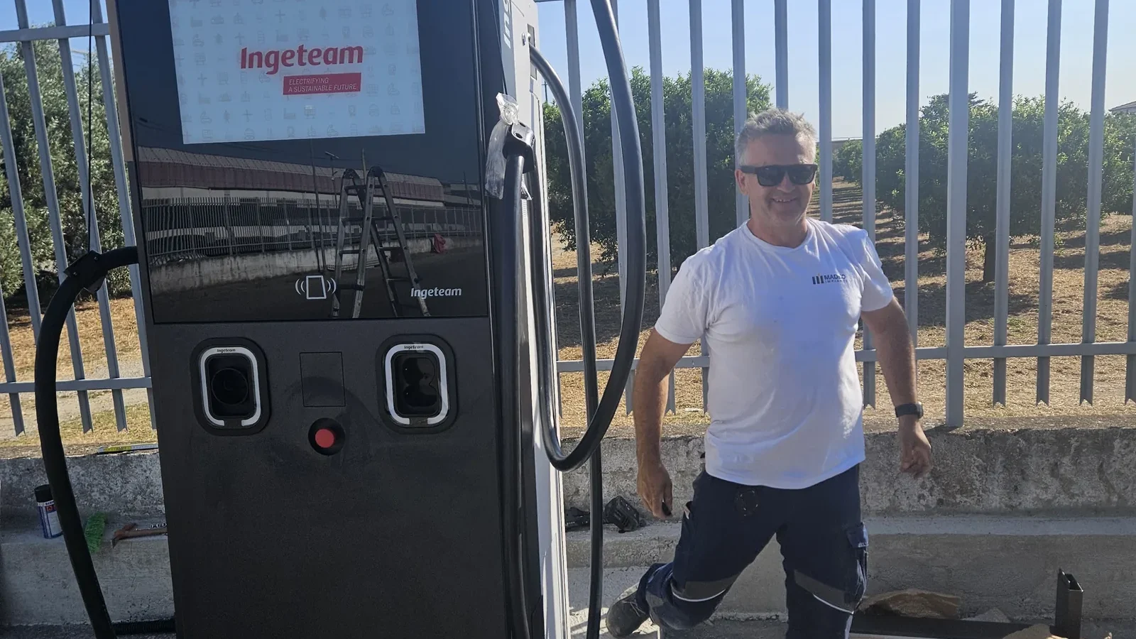 Colonnina di ricarica rapida Ingeteam installata su plinto, con un tecnico di Madeo Impianti accanto